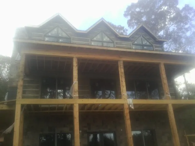 Dormers and porch framing on a large log home under construction — Roof Coating work by our crew in Barton