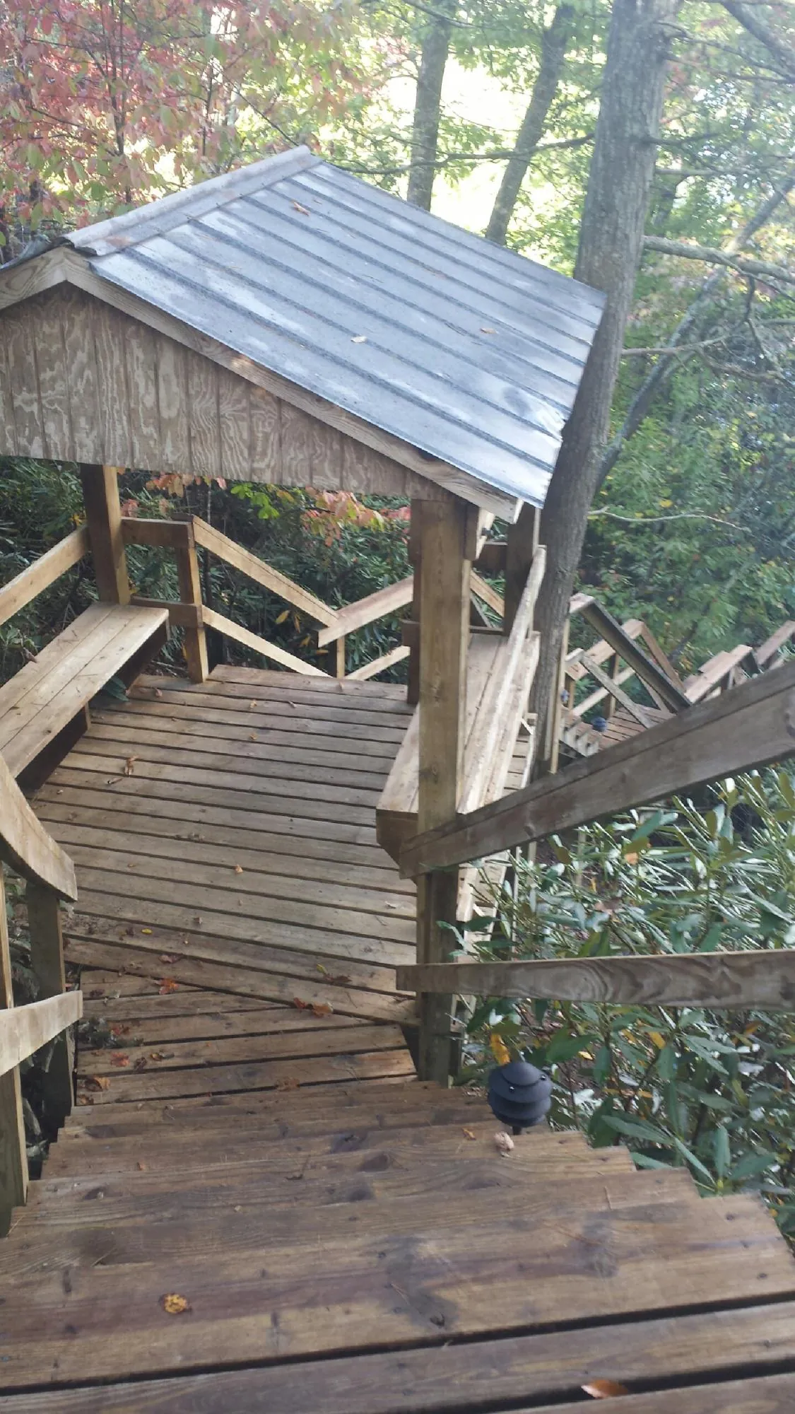 Metal roofed shelter over wooden steps on a wooded walkway — Skylight Repair & Installation work by our crew in Barton